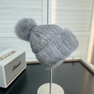 Detail view of a grey winter hat featuring quilted texture and soft fur trim with pom-pom.