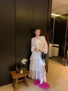 Asian model styling pink Mongolian fur slides with a white dress in indoor setting
