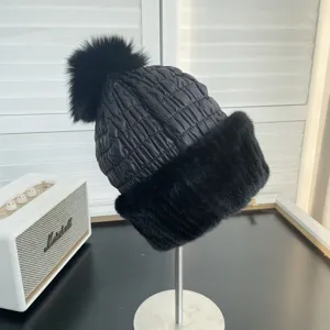 Detailed view showing the black winter hat with a large fox fur pom-pom and mink brim