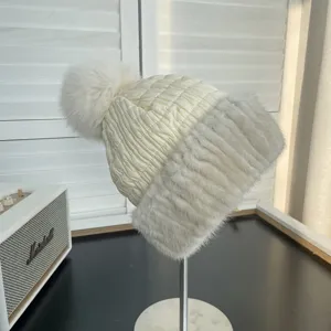 White quilted down hat with gray mink fur trim and fox fur pompom detail