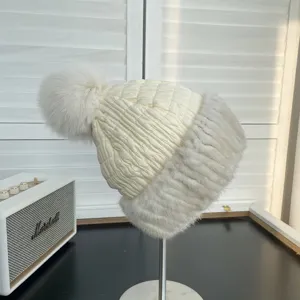 Detailed view of quilted winter hat with fluffy fox fur pom-pom and mink fur trim