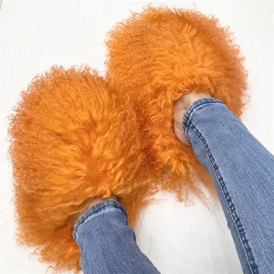 Close-up of vibrant orange Mongolian fur slides worn with blue jeans