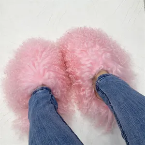 Close-up detail of fluffy pink Mongolian sheep fur slides worn with blue denim jeans.