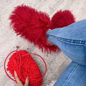 Detailed view of vibrant red Mongolian fur slides paired with a matching fluffy textured bag