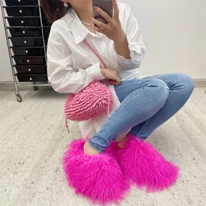 Close-up of fluffy hot pink Mongolian fur slides worn with a white shirt and jeans