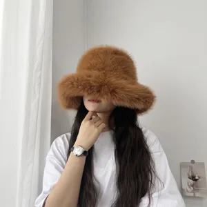 Détail d'un chapeau bob en fausse fourrure marron avec un large bord, porté par un modèle.