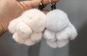 Close-up of soft pink and grey mink fur rabbit keychains held in hand