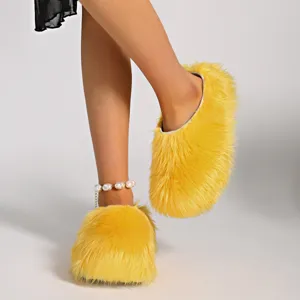 Vista detallada de las pantuflas con plataforma de pelo sintético amarillo brillante