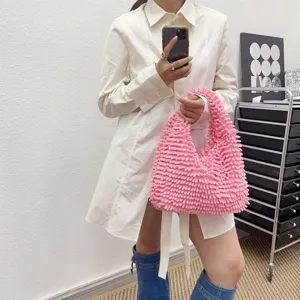 Texture détaillée d'un sac à main en chenille rose duveteux tenu par un mannequin