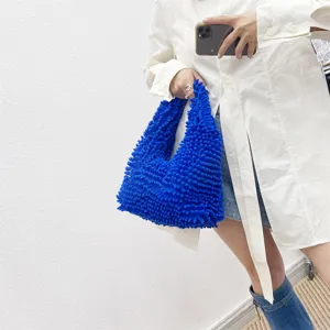 Vue détaillée d'un sac cabas bleu vif en chenille texturée tenu par un modèle.
