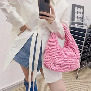 Sac à main rose pelucheux style serpillère porté par une personne avec une tenue élégante