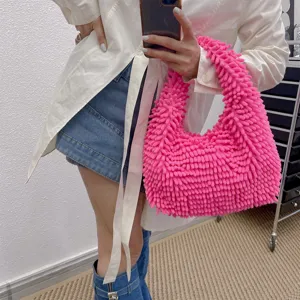 Sac hobo texturé en peluche rose bonbon tenu par un mannequin devant un miroir.