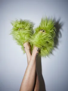 Photo artistique de pantoufles en fausse fourrure vert néon style punk Y2K sur modèle