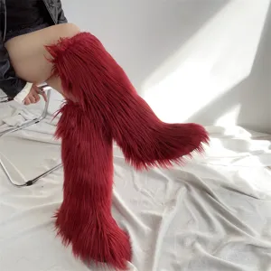 Stylish red faux fur knee-high boots with long plush texture shown from a side angle on a model