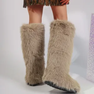 Detailed view of warm Y2K knee-high faux fox fur snow boots on a model in a studio setting.
