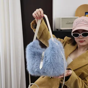 Model hält eine süße blaue Webpelz-Umhängetasche mit weißem Riemen und silbernem Verschluss.