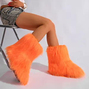 Gros plan sur des bottes de neige orange vif en fausse fourrure pour un look Y2K