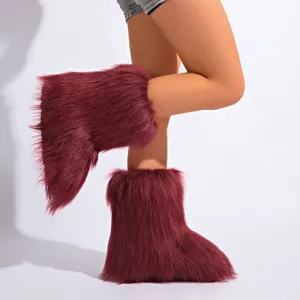 Gros plan sur des bottes de neige en fausse fourrure bordeaux portées par un mannequin.