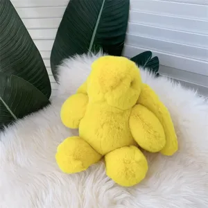 Détail rapproché d'un lapin en peluche jaune avec de longues oreilles sur un tapis blanc