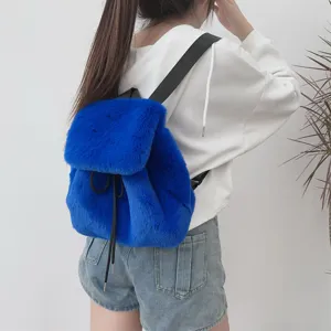 Junges Mädchen mit einem leuchtend königsblauen Plüschrucksack aus Kunstpelz und Kordelzug