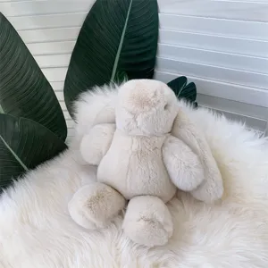 Détail d'un lapin en peluche crème doux reposant sur un tapis blanc moelleux