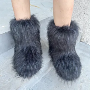 Close-up of black fluffy faux fur snow boots in Y2K style on grey concrete steps