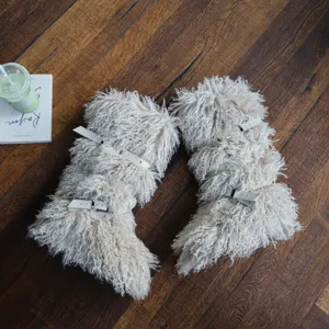 Dettaglio degli stivali da neve in ecopelliccia beige con fibbie e borchie alla moda