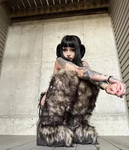 Edgy model showcasing Y2K style oversized faux fur knee-high boots in a street fashion setting