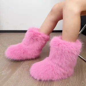 Détail rapproché de bottes de neige en fausse fourrure rose avec texture moelleuse.