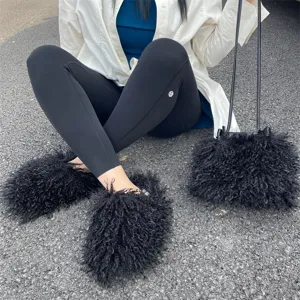 Détail des chaussons noirs en fausse fourrure de mouton et sac à main en peluche assorti.