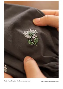 Close-up detail of white flower embroidery on premium dark grey cotton over-sleeves