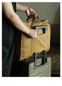 Dettaglio della borsa da viaggio fissata al manico di una valigia tramite la fascia posteriore.