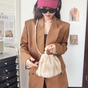 Detailaufnahme einer flauschigen beigen Beuteltasche aus Kunstnerzfell, gehalten von einem Model