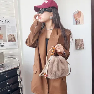 Detailaufnahme einer weichen Kunstpelz-Handtasche mit Perlengriff und Schultergurt