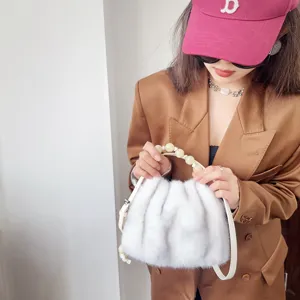Makroansicht der weißen Kunstpelz-Handtasche mit stilvollem Perlengriff und Riemen.