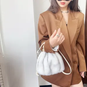 Detailansicht einer weißen Eimer-Tasche aus Nerzimitat mit einem Lederarmband