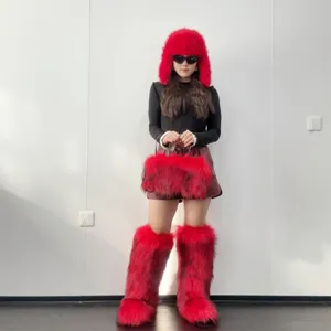 A complete set of vibrant red Y2K style faux fur knee-high boots, hat, and tote bag on model