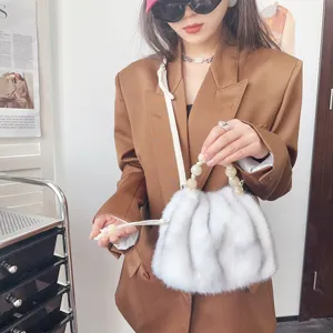Mode-Model trägt eine graue Kunstfell-Beuteltasche mit elegantem Perlengriff und braunem Blazer