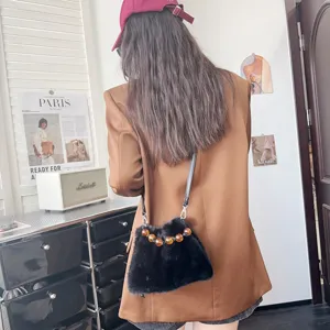 Elegante schwarze Umhängetasche aus Kunstfell mit modischen bernsteinfarbenen Perlen