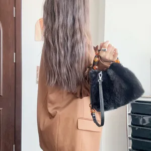 Detailansicht einer luxuriösen schwarzen Handtasche aus Kunstpelz mit Bernsteinperlen