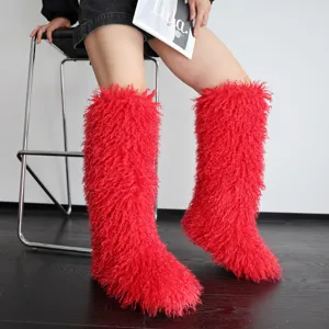 Detailopname van felrode pluizige kniehoge laarzen van imitatiebont voor dames