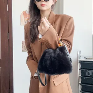 Detailansicht der schwarzen Handtasche aus Nerzimitat, kombiniert mit einem braunen Blazer