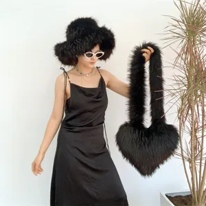 Gros plan d'un chapeau en fausse fourrure noire et d'un sac à main en forme de cœur
