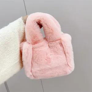 Vista detallada que muestra la suave textura de un mini bolso tote de peluche rosa de pelo sintético