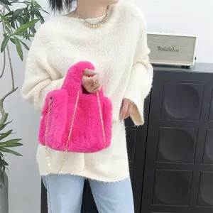 Detalle de mini bolso rosa de pelo sintético con cadena dorada llevado por modelo.