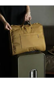 Dettaglio ravvicinato che mostra la borsa da viaggio senape montata su una valigia di lusso