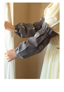 Close-up of elegant grey cotton oversleeves with delicate floral embroidery for work