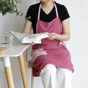 Elegante delantal de cocina de algodón rosa con bolsillo lateral, ideal para cocinar y café.