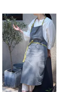 Dettaglio di un grembiule in cotone e lino grigio con cinghie verdi in un giardino