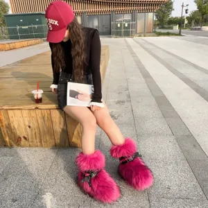 Hot pink faux fur Y2K platform snow boots with punk rivet straps worn by model outdoors